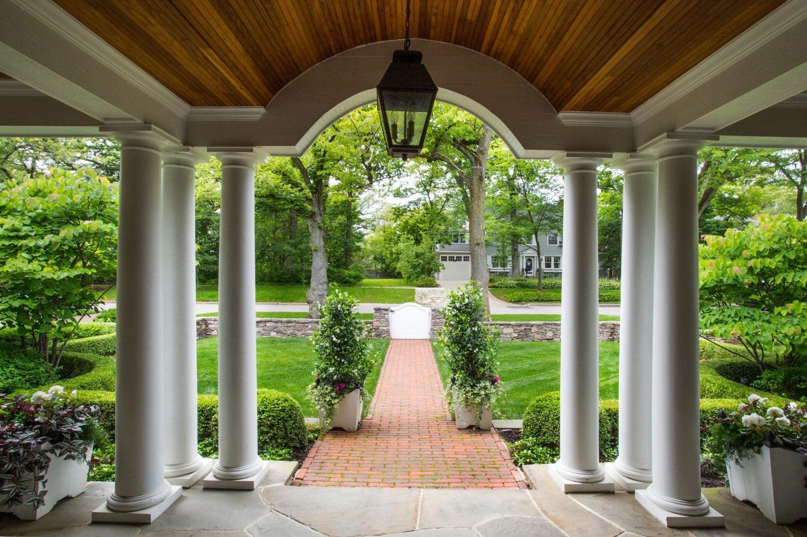 Covered porch with columns overlooking manicured front lawn